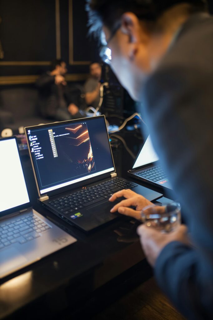 Focused IT professional working on laptop coding in a dimly lit office setting.